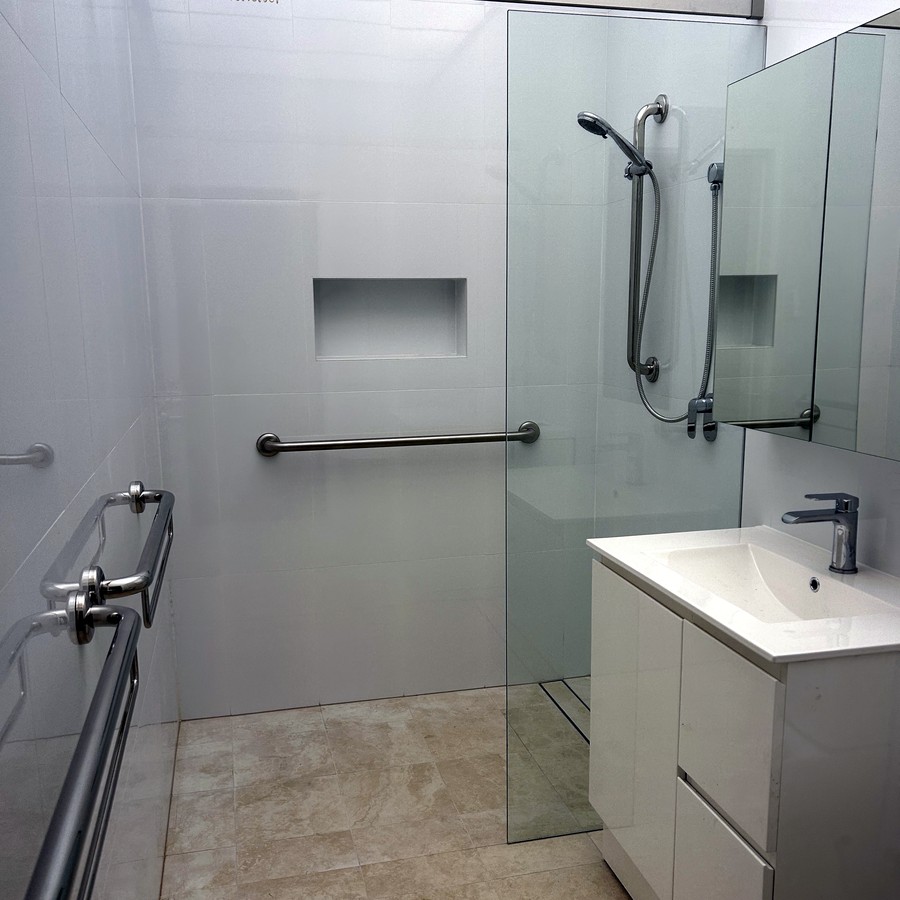 Walk-in shower with angled grab rail and hand-held shower