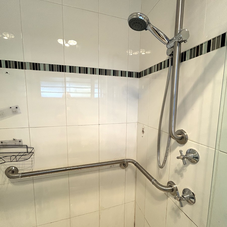 Walk-in shower with a long angled grab rail