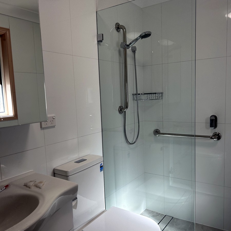 Accessible bathroom with a glass-screen walk-in shower and grab rail
