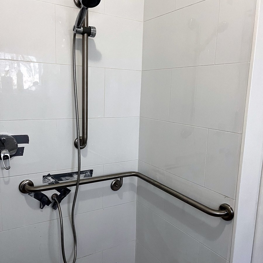 Angled grab rail and hand-held shower in an accessible bathroom