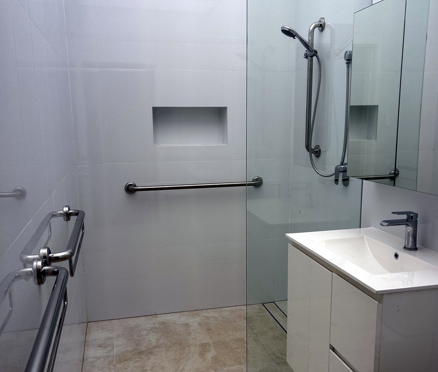 Accessible bathroom with a shower grab rail, hand-held shower rail and fold-down rails installed by Access at Home in Sydney