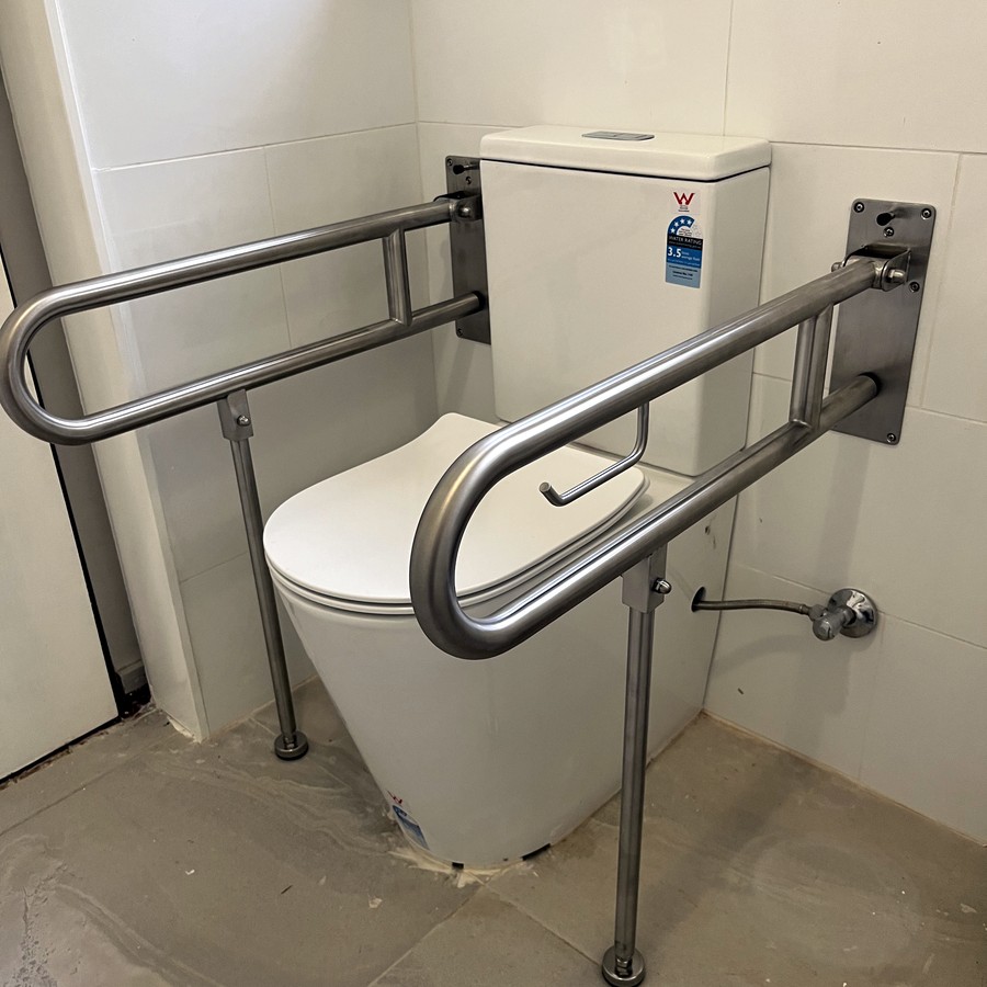 Fold-down and angled grab rails beside a toilet