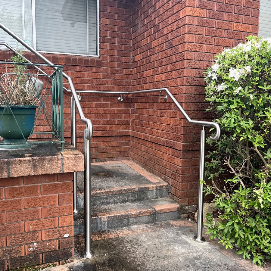 Curved stainless steel handrail on brick entry steps