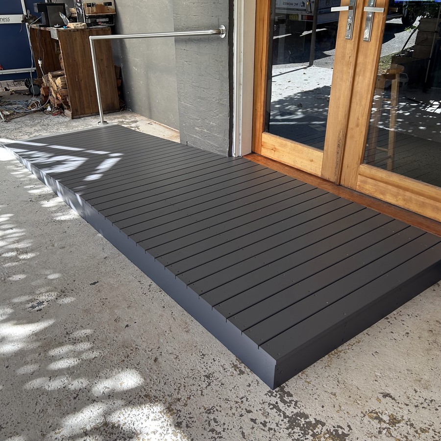Dark composite access ramp to a glass sliding door