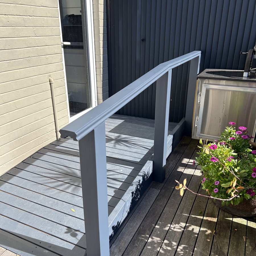 Timber deck ramp with a handrail at a home entrance
